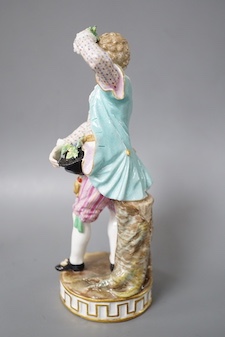 A 19th century Meissen figure of a boy holding grapes to his head, his hat full of grapes, wearing a crinoline scarf and shirt cuffs, crossed swords in blue, incise letters and numbers 17cm